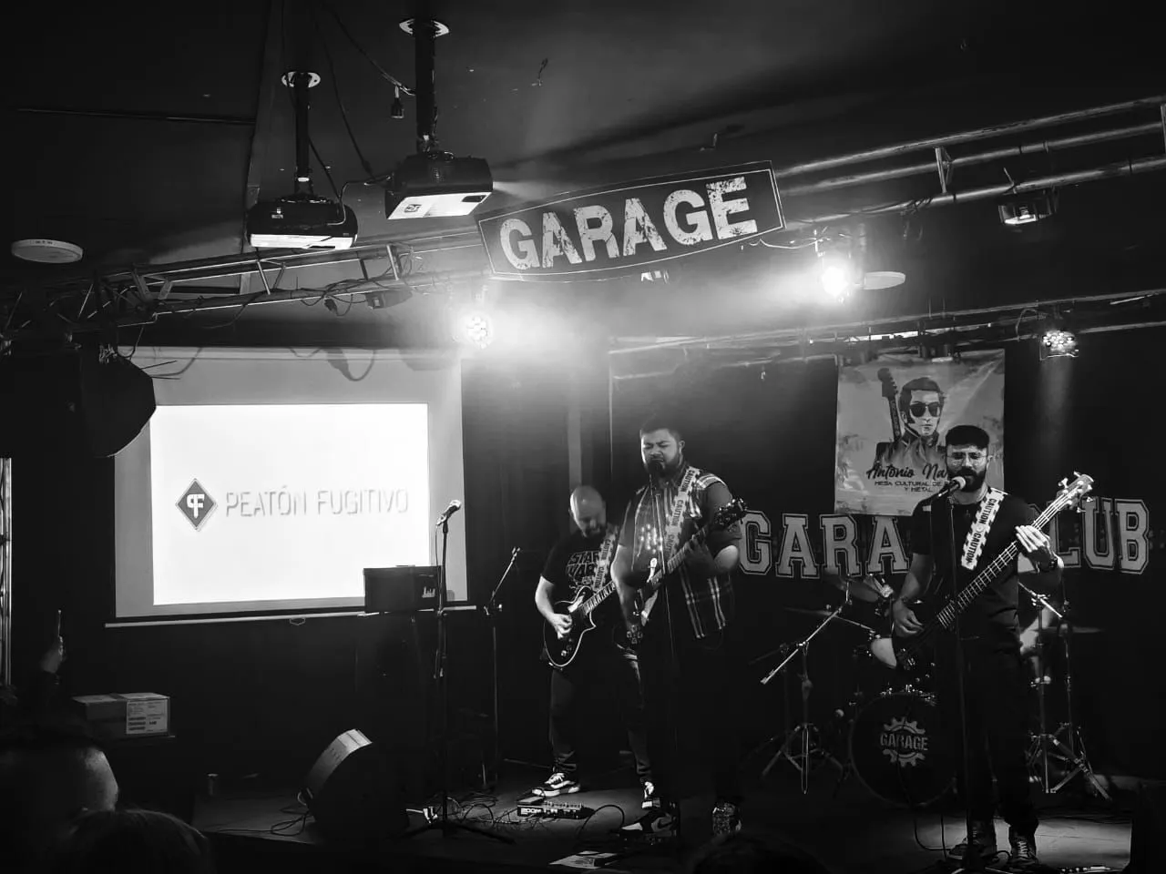 La banda tocando en Garage Club con proyección del logo