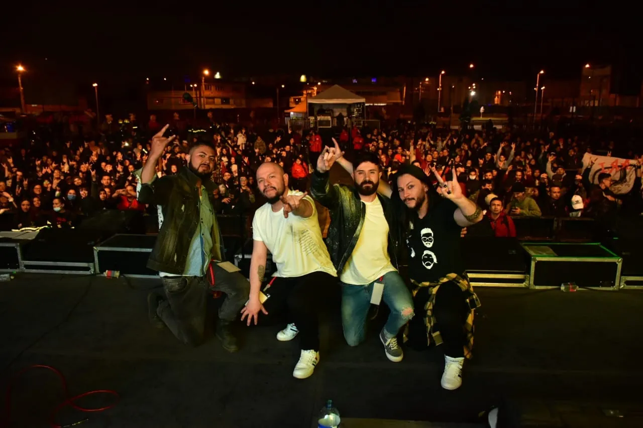 La banda con la multitud nocturna haciendo el gesto del rock